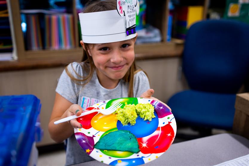 A girl smiles while holding a plate